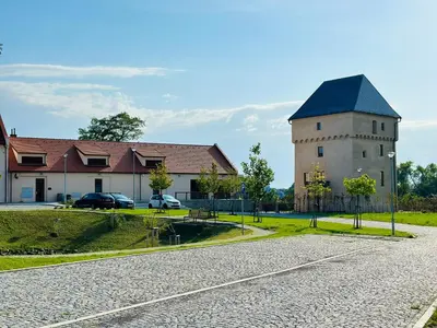 a building with a tower next to a house at STUDIO KRÁLOVICE Apartment in Prague