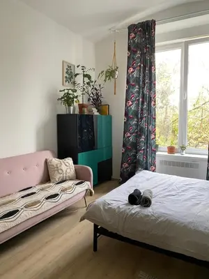 a bedroom with a bed and a couch and a window at Cute botanical flat near by Žižkov tower in Prague