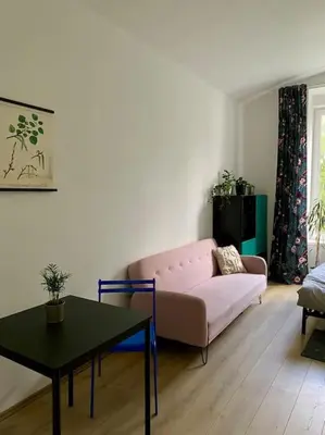a living room with a pink couch and a table at Cute botanical flat near by Žižkov tower in Prague