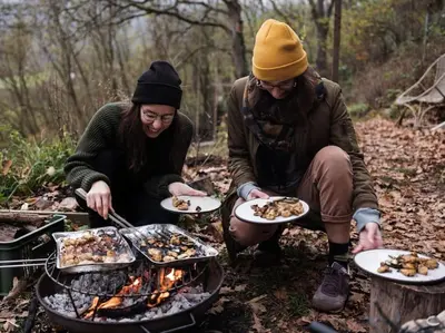 a man and woman cooking food over a fire at Sušárna v zahradě s vůní bylinek in Křivoklát