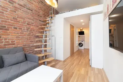 a living room with a couch and a brick wall at Mezzanine Beds, 10min to Centre with Offsite Parking in Prague