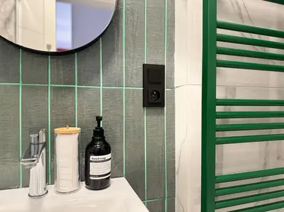 a bathroom sink with a bottle of soap and a mirror at Red Currant - Prague Apartment in Prague