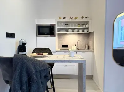 a small white kitchen with a table and chairs at Red Currant - Prague Apartment in Prague