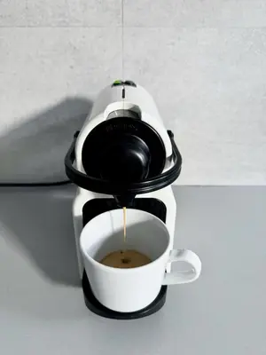 a coffee maker is pouring coffee into a cup at Apartment by Charles Bridge in Prague