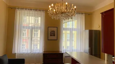 a dining room with a chandelier and two large windows at Apartmán v centru Prahy in Prague