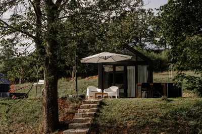 a house with a table and chairs and an umbrella at Glamping Osada in Hyskow