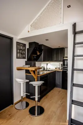 a kitchen with black cabinets and a bar with stools at Glamping Osada in Hyskow