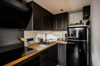a kitchen with black cabinets and a black refrigerator at Glamping Osada in Hyskow