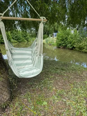 a white hammock hanging from a tree next to a river at Glamping Osada in Hyskow