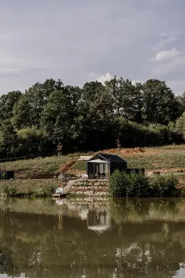 a small cabin next to a body of water at Glamping Osada in Hyskow