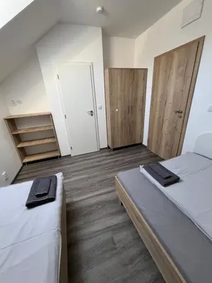 two beds in a room with wooden floors at Penzion Kopanský mlýn in Statenice