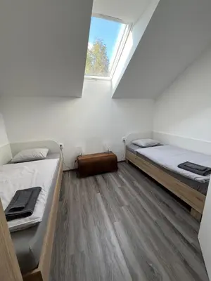 two beds in a small room with a window at Penzion Kopanský mlýn in Statenice