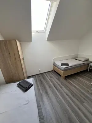 a small room with two beds and a window at Penzion Kopanský mlýn in Statenice