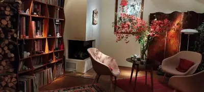 a living room with two chairs and a table and bookshelves at Guestrooms, rooftop with garden, spacious living room, character and fireplace in Prague