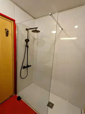 a shower with a glass door in a bathroom at Guestrooms, rooftop with garden, spacious living room, character and fireplace in Prague