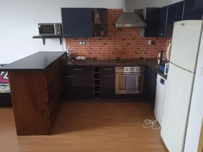a kitchen with black cabinets and a white refrigerator at Byt Vinoř in Prague