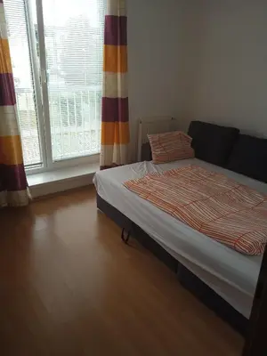 a bedroom with a bed and a large window at Byt Vinoř in Prague