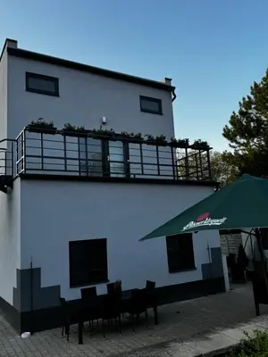 a building with a table and a green umbrella at Apartmán 1 Jägerhaus in Radovesice