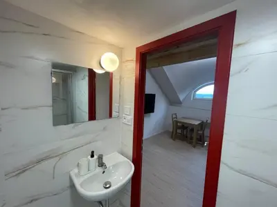 a white bathroom with a shower and a toilet at Hotel Vinařice Česky kras in Měňany