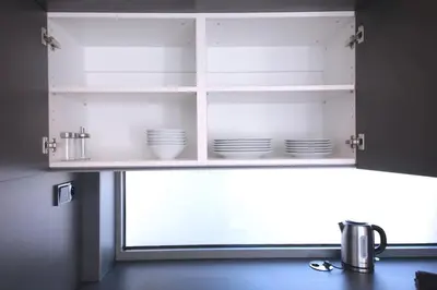 a white cabinet with dishes in it with a window at Spacious Top Floor Flat, Air Conditioning, Free Parking, 200Mb WiFi in Prague