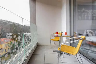 a balcony with a table and chairs and a bed at On-site Free Parking, 12 to min Centre, Supermarket in Prague