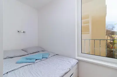 a bed with blue pillows sitting next to a window at Peace and Comfort Near Center with Balcony, 500MB WIFI in Prague