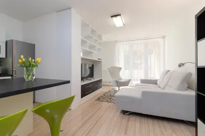 a white living room with a couch and a tv at Peace and Comfort Near Center with Balcony, 500MB WIFI in Prague