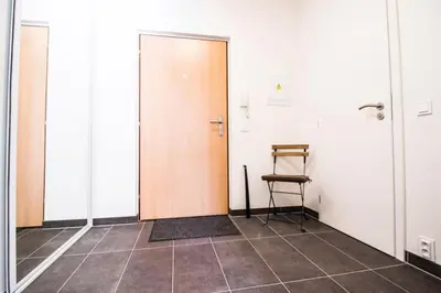 a hallway with two doors and a chair in it at Stylish Studio with Balcony, 12 Min to City Centre, Free Netflix & WiFi in Prague