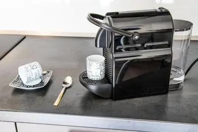 a black toaster sitting on a counter with a cup and spoon at Stylish Studio with Balcony, 12 Min to City Centre, Free Netflix & WiFi in Prague