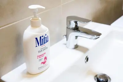a bottle ofinator detergent sitting on a bathroom sink at Stylish Studio with Balcony, 12 Min to City Centre, Free Netflix & WiFi in Prague