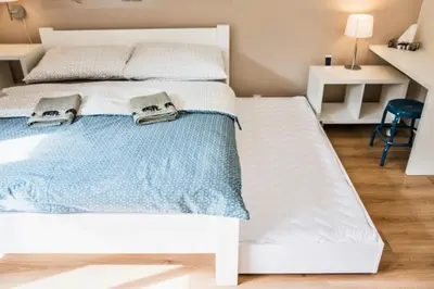 a white bed with two towels on top of it at Stylish Studio with Balcony, 12 Min to City Centre, Free Netflix & WiFi in Prague