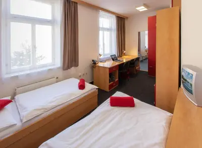 a room with two beds and a desk with a computer at Masarykova Kolej in Prague