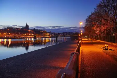 a bench sitting next to a river at night at Royal Residence Vysehrad Prague in Prague