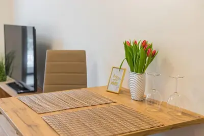 a table with wine glasses and a vase with flowers at Flat with Bathtub & Balcony, only 12min Centrum, 200Mb WIFI in Prague