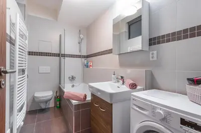 a bathroom with a sink and a washing machine at Flat with Bathtub & Balcony, only 12min Centrum, 200Mb WIFI in Prague