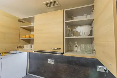 a kitchen with wooden cabinets with wine glasses at Flat with Bathtub & Balcony, only 12min Centrum, 200Mb WIFI in Prague