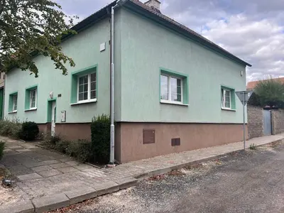 a green house with windows on the side of a street at Apartmán se společným bazénem Zlonice in Zlonice