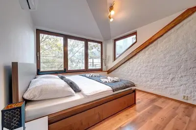a bedroom with a large bed in a room with windows at Đã Về - Đã Tới in Prague