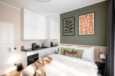 a bedroom with a white bed and a kitchen at Accordion Boutique Hotel & Premium Suites in Prague