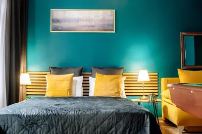 a bedroom with a blue wall and a bed with yellow pillows at Wagnerstays Royal Billiard Residence in Prague