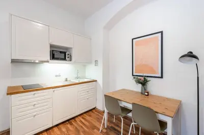 a kitchen with white cabinets and a wooden table at Adorable Cozy Studio in Central Prague in Prague