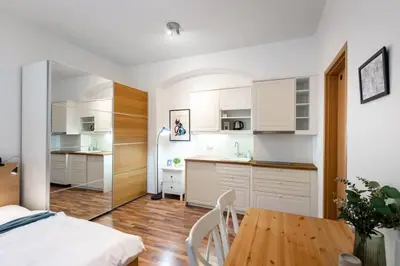 a kitchen with white cabinets and a wooden table at Beautiful Cozy Studio Gem near Old Town in Prague