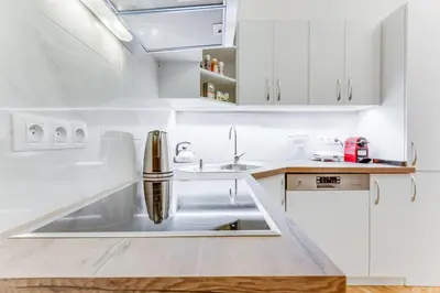 a white kitchen with a sink and white cabinets at Prague Days - Three-bedroom Apartment with Balcony in Prague