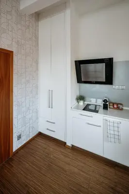 a kitchen with white cabinets and a tv on a wall at Prague Days - Studio in a prime location with AC close to the Charles Bridge in Prague