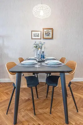 a dining room table with chairs and a black table with flowers at Prague Days - Apartment with 2 Bedrooms and 2 Balconies in Vinohrady in Prague