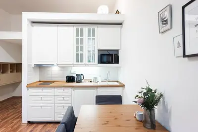 a kitchen with white cabinets and a wooden table at Modern Loft Getaway in Prague