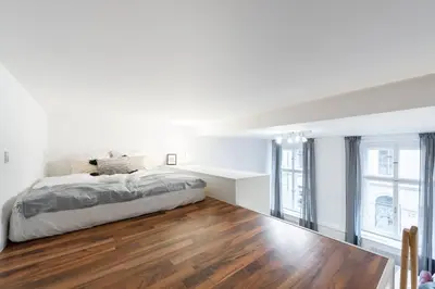 a white bedroom with a bed and wooden floors at Modern Loft Getaway in Prague