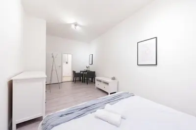 a white bedroom with a bed and a table at Timeless Charming Studio near Old Town in Prague