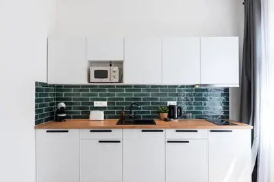 a kitchen with white cabinets and a green tile wall at Unique Old Town 2BR Oasis with Sofa Bed in Prague