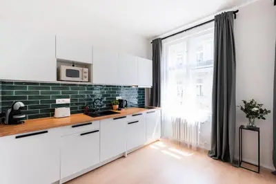 a kitchen with white cabinets and a large window at Unique Old Town 2BR Oasis with Sofa Bed in Prague